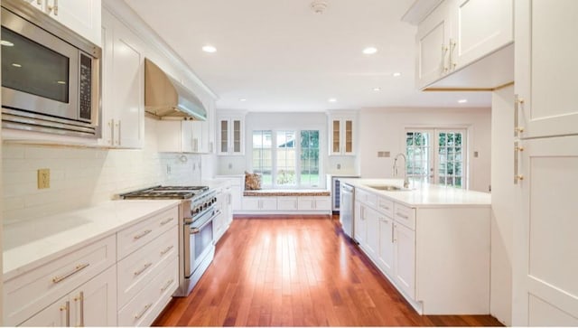 kitchen with white cabinetry, appliances with stainless steel finishes, and wall chimney range hood