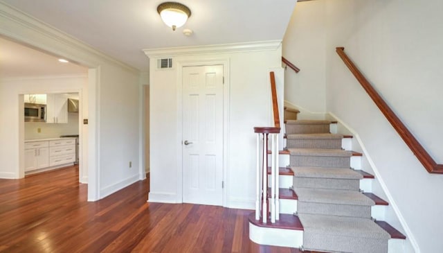 stairway featuring crown molding and hardwood / wood-style floors