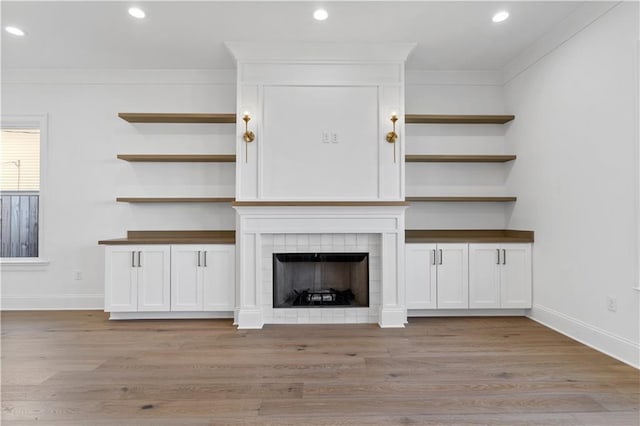 unfurnished living room with crown molding, a fireplace, and light wood-type flooring