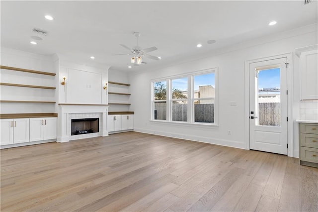 unfurnished living room with ceiling fan, ornamental molding, a fireplace, and light wood-type flooring