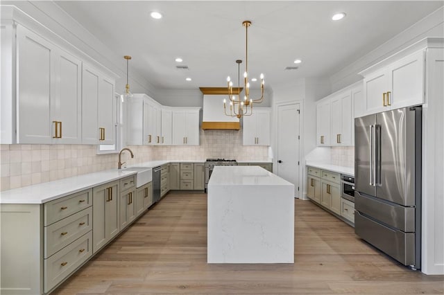 kitchen featuring sink, high end appliances, a center island, hanging light fixtures, and white cabinets