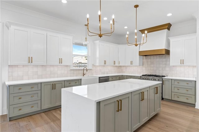 kitchen featuring decorative light fixtures, white cabinetry, sink, a center island, and crown molding