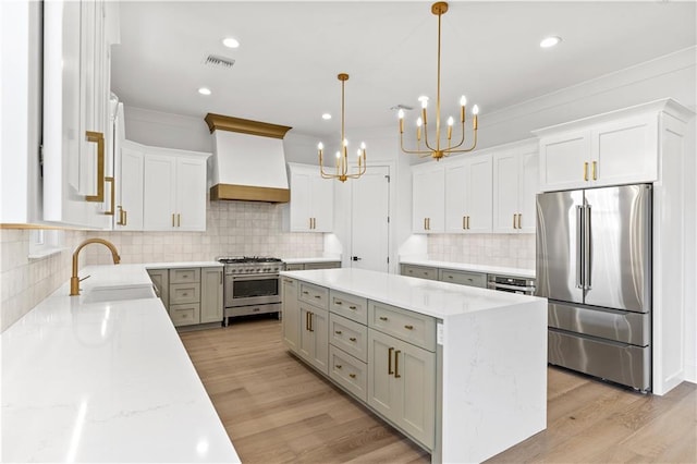 kitchen featuring premium range hood, white cabinetry, hanging light fixtures, stainless steel appliances, and light stone countertops