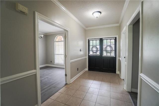 tiled foyer entrance featuring crown molding and a textured ceiling