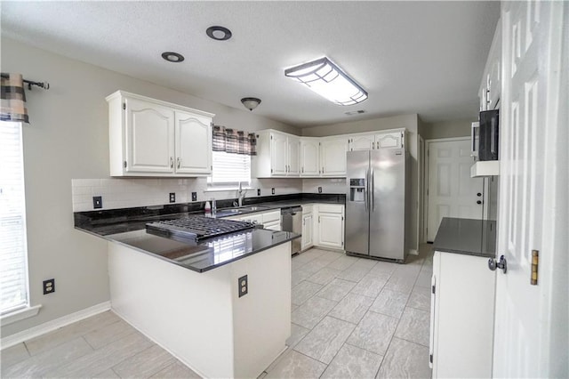 kitchen featuring appliances with stainless steel finishes, tasteful backsplash, white cabinetry, sink, and kitchen peninsula