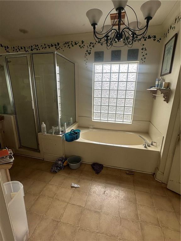 bathroom featuring plus walk in shower and a chandelier