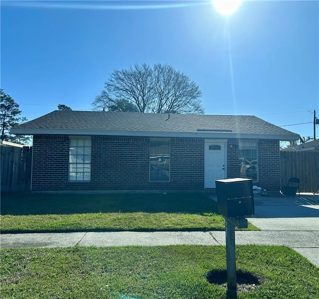 single story home featuring a front yard, fence, and brick siding