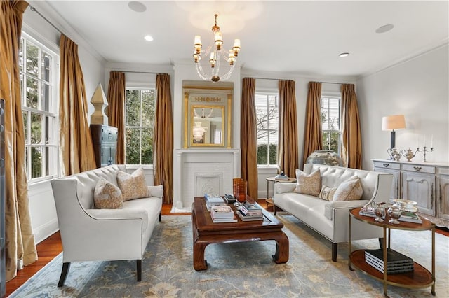 living area with hardwood / wood-style flooring, crown molding, a healthy amount of sunlight, and a chandelier