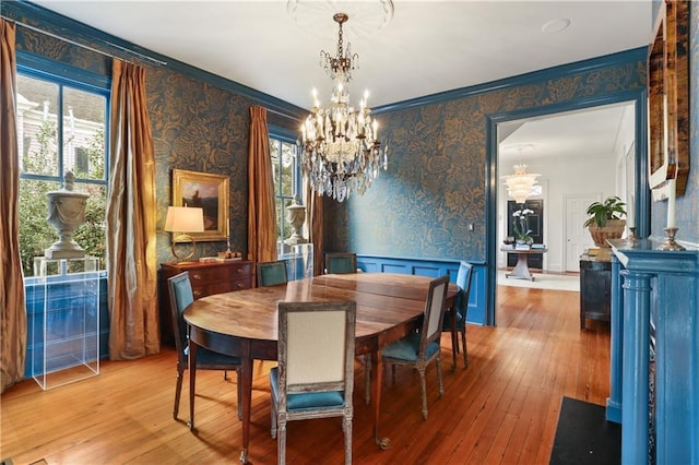 dining area with an inviting chandelier, ornamental molding, and hardwood / wood-style flooring