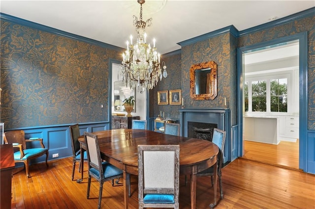 dining area with crown molding, wood-type flooring, and a chandelier