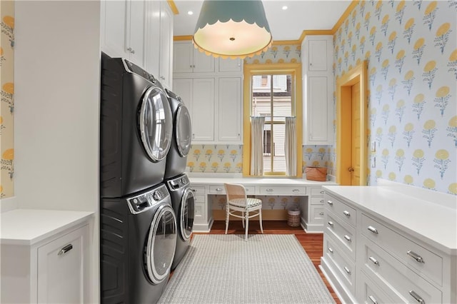 laundry area with cabinets, stacked washer / drying machine, and dark hardwood / wood-style flooring