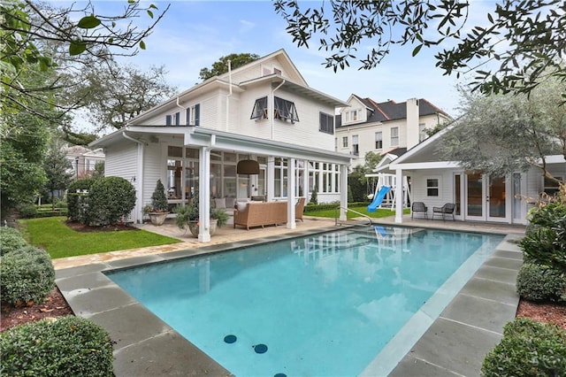 rear view of property with an outdoor living space, an outbuilding, and a patio area