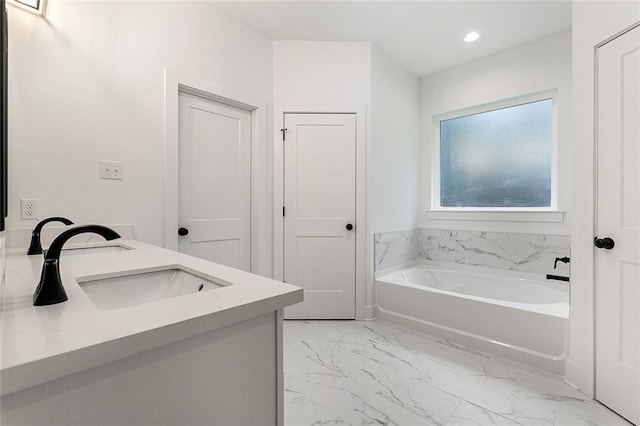 bathroom featuring marble finish floor, a sink, double vanity, a bath, and recessed lighting