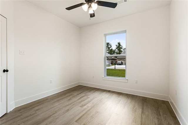 spare room featuring light wood-style flooring, baseboards, a ceiling fan, and visible vents