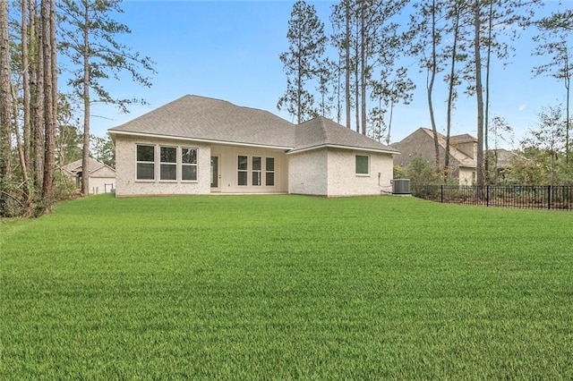 rear view of property with roof with shingles, fence, central air condition unit, and a yard