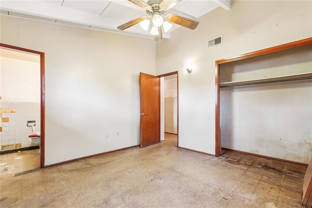 unfurnished bedroom featuring ensuite bath, beam ceiling, and a closet