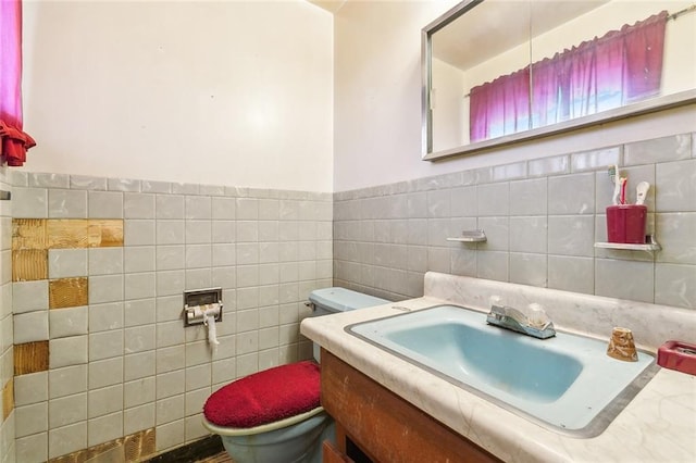 bathroom with vanity, toilet, and tile walls