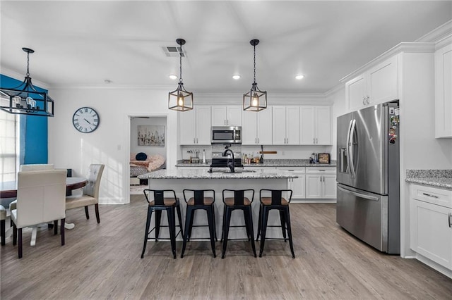 kitchen with sink, light stone counters, white cabinetry, hanging light fixtures, and stainless steel appliances