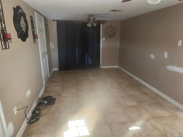 spare room with ceiling fan, visible vents, and baseboards