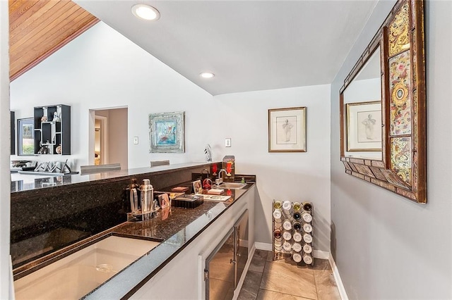 bathroom with a sink, recessed lighting, double vanity, baseboards, and vaulted ceiling