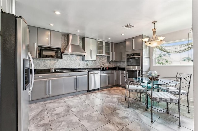 kitchen with visible vents, gray cabinetry, dark countertops, stainless steel appliances, and wall chimney exhaust hood