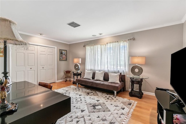 living area featuring visible vents, light wood-style flooring, crown molding, and baseboards