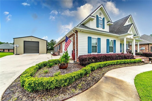 view of front of home with brick siding, a shingled roof, concrete driveway, a garage, and an outdoor structure