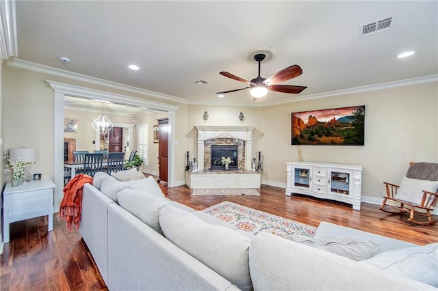 living room with a fireplace, wood finished floors, visible vents, baseboards, and ornamental molding