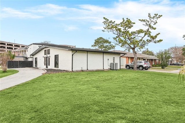 view of property exterior with central AC and a lawn