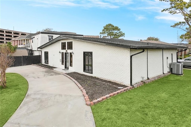 rear view of property featuring a yard, central AC unit, and a patio area