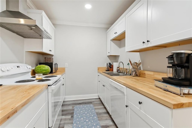 kitchen with white appliances, a sink, wood counters, wall chimney exhaust hood, and light wood finished floors