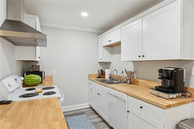 kitchen with white appliances, wood counters, crown molding, wall chimney range hood, and a sink