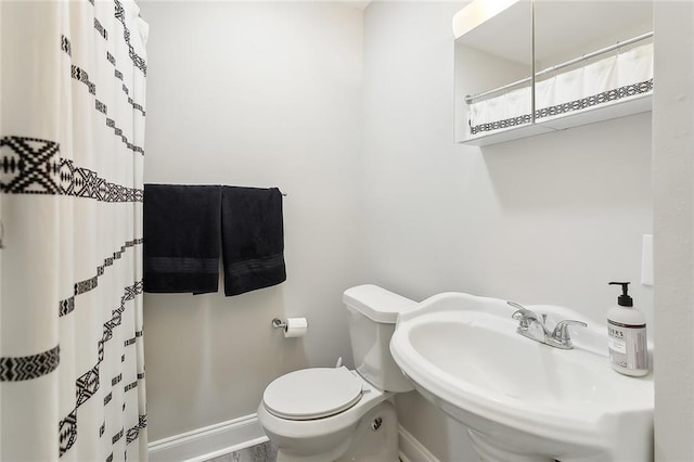 full bath featuring a shower with shower curtain, a sink, toilet, and baseboards