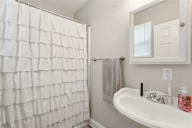 full bath with curtained shower and a sink