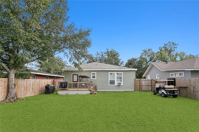 rear view of property featuring a fenced backyard, a lawn, and a deck