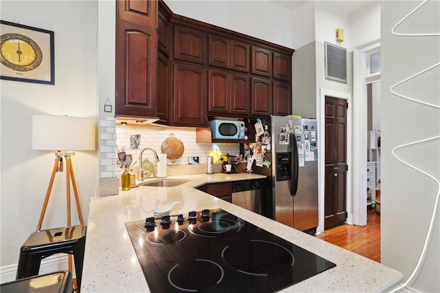 kitchen with tasteful backsplash, stainless steel appliances, light stone countertops, and sink