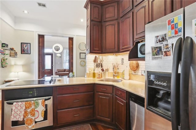 kitchen with tasteful backsplash, stainless steel appliances, kitchen peninsula, and sink