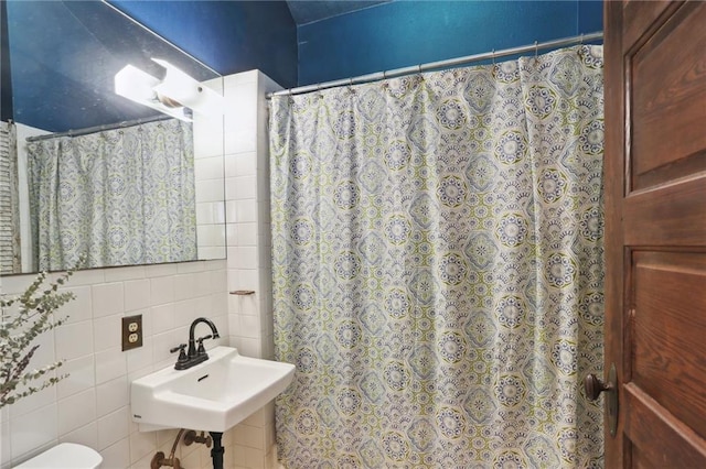 bathroom with sink, tile walls, and toilet