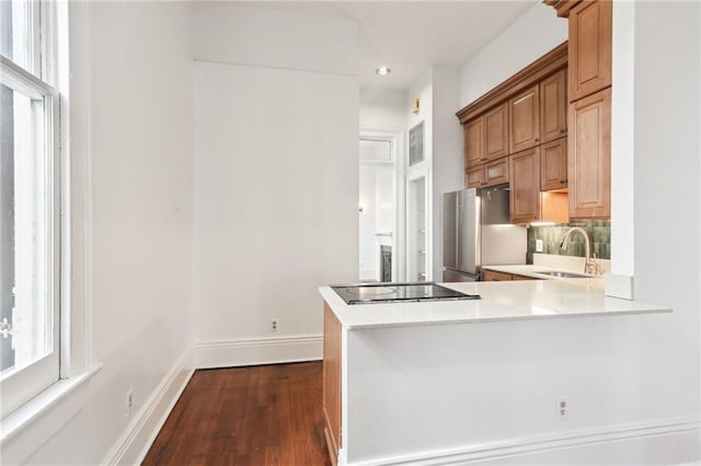 kitchen featuring sink, stainless steel fridge, dark hardwood / wood-style flooring, backsplash, and kitchen peninsula