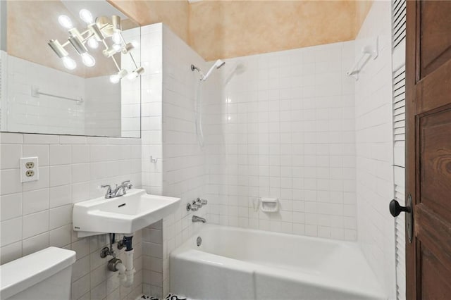 full bathroom featuring tile walls, sink, tiled shower / bath combo, and toilet