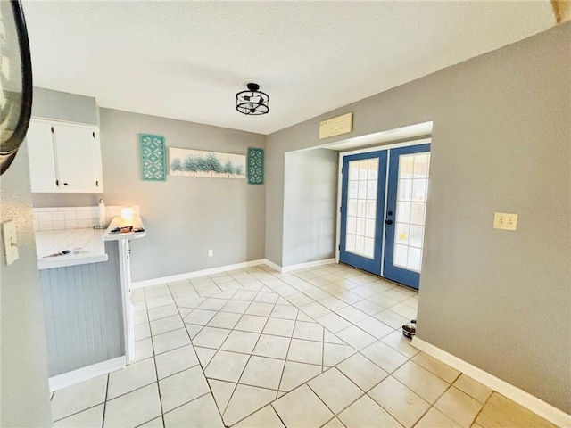 unfurnished dining area featuring french doors and light tile patterned flooring