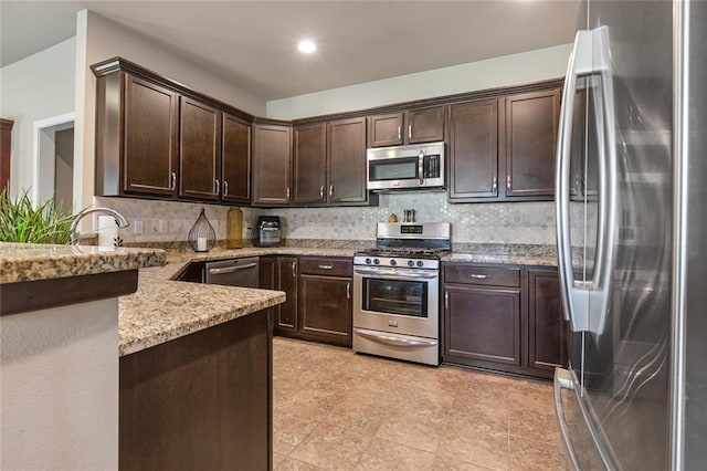 kitchen featuring stainless steel appliances, light stone countertops, and dark brown cabinets