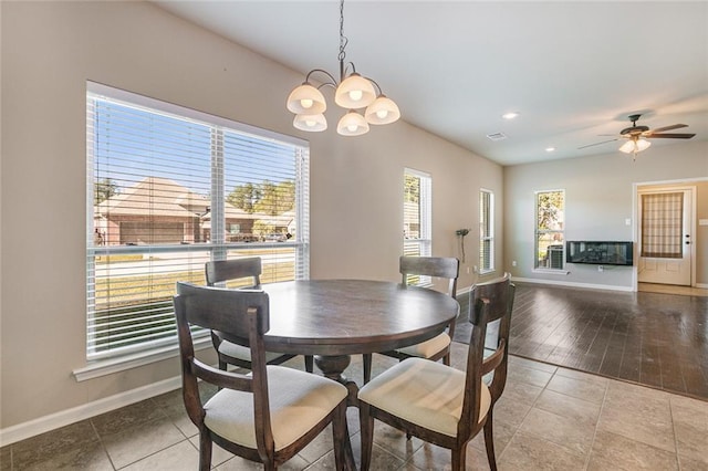 tiled dining room with ceiling fan with notable chandelier