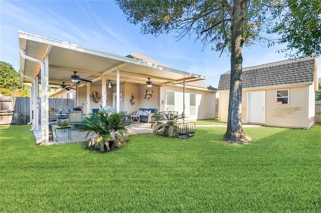 rear view of house with an outbuilding, ceiling fan, a yard, and a patio area