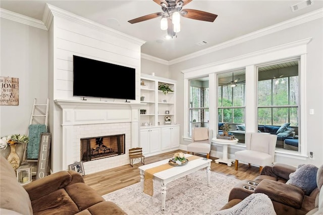 living room with crown molding, a fireplace, visible vents, and wood finished floors