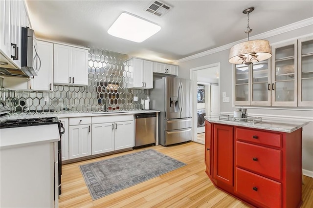 kitchen featuring decorative light fixtures, tasteful backsplash, sink, stacked washer / drying machine, and stainless steel appliances