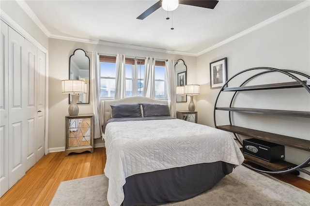 bedroom with ornamental molding, ceiling fan, light wood-type flooring, and a closet