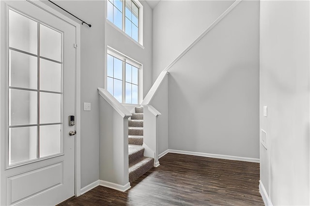 foyer entrance with dark wood-type flooring and a towering ceiling