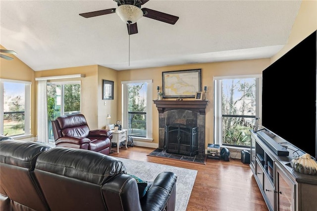 living room featuring ceiling fan, vaulted ceiling, hardwood / wood-style floors, and a fireplace