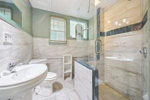 2226 Saint Bernard Ave, New Orleans, LA 70119 - full bath with tile walls, a shower stall, wainscoting, and marble finish flooring